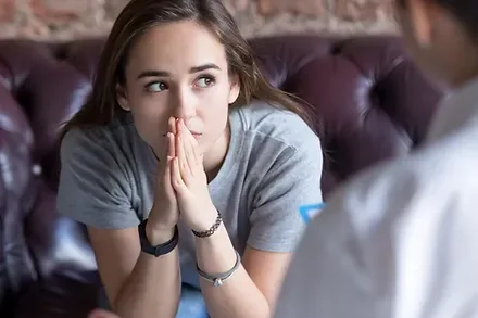 A young woman in conversation with a counsellor, leaning forward mid-sentence