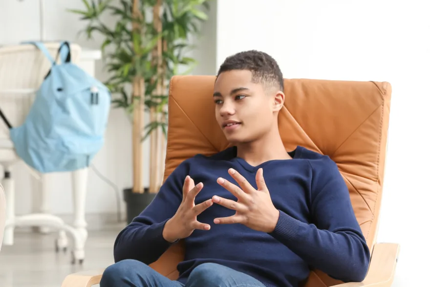 A young man sitting in an armchair, talking openly in a counselling session