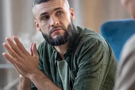 A man talking with his hands as he explains something to a counsellor